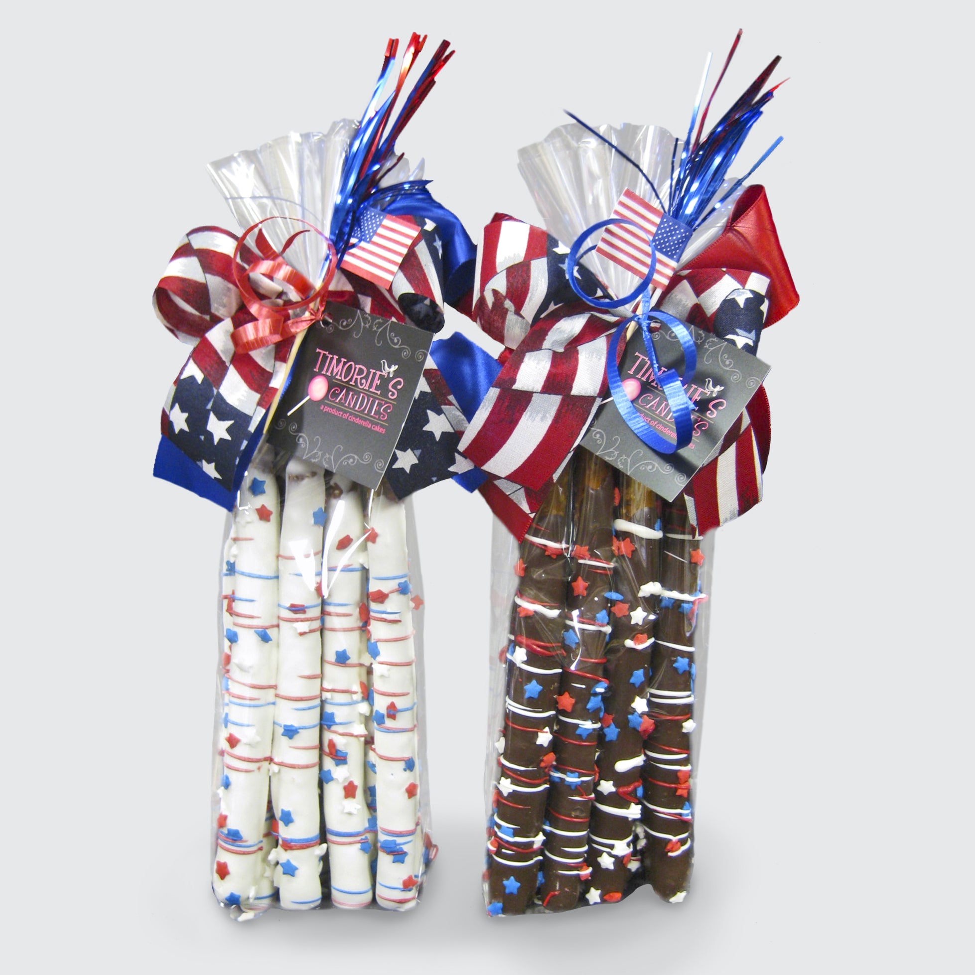 One bag of six white chocolate-covered pretzel rods and one bag of six dark chocolate-covered pretzel rods. Each rod is decorated with red, white, and blue drizzle and topped with star-shaped sprinkles. Each bag is tied with a festive patriotic ribbon and a mini USA flag.