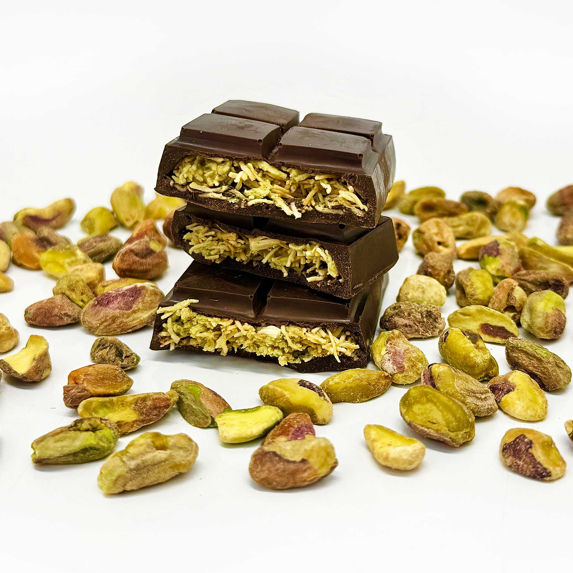 Three pieces of the Dubai Chocolate bar that's filled with pistachio cream, tahini, and crispy kataifi dough, are stacked on top of each other