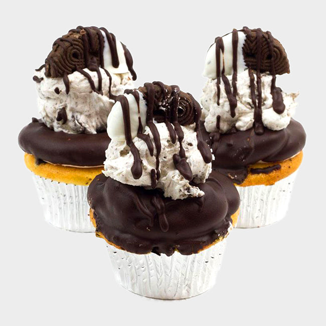 Three Cookies & Cream Blast cupcakes topped with a buttercream swirl dipped in chocolate then topped with a scoop of cookies 'n cream filling, adorned with a white chocolate dipped Oreo cookie and drizzled with chocolate ganache
