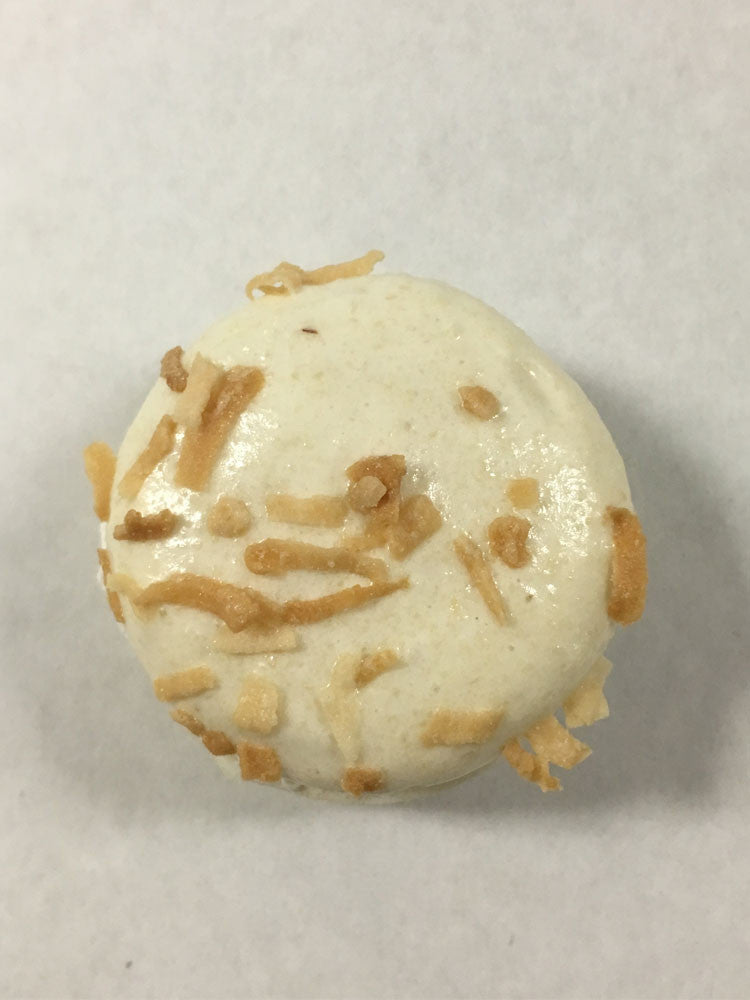 A toasted coconut macaron with a cream color shell and toasted coconut topping