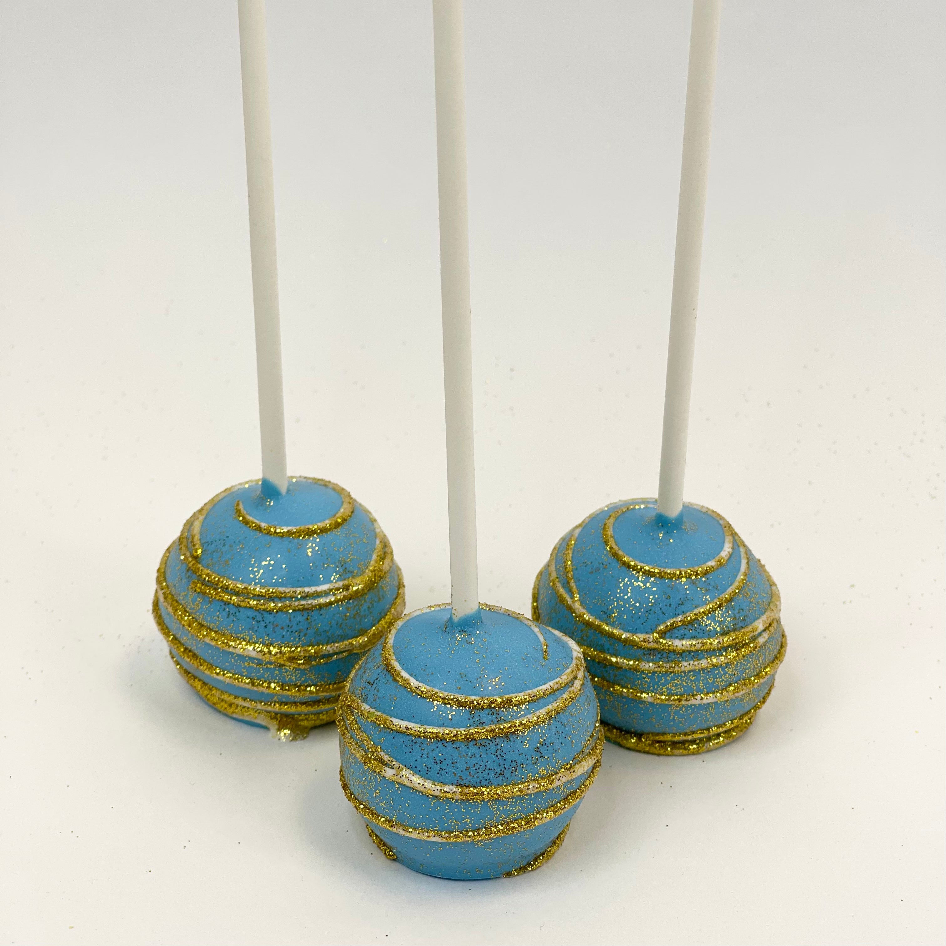 Three Cake Pop dipped in blue chocolate with white swirl dust in gold glitter