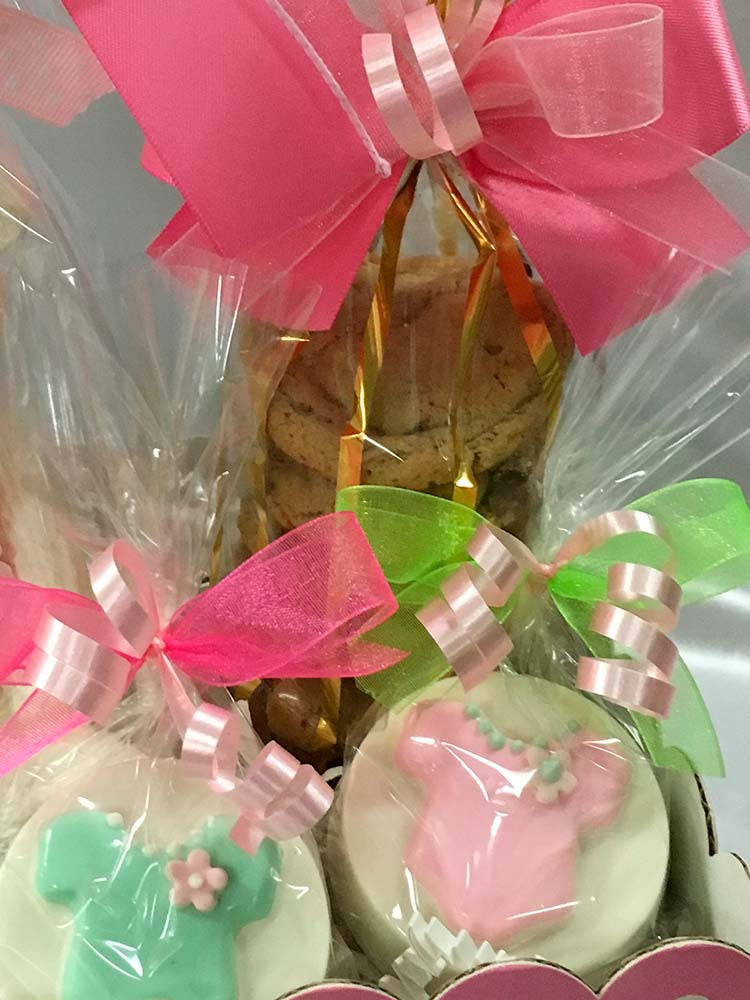 It's A Girl git box: 2 bags of mini chocolate chip cookies, solid 3D white chocolate bear, chocolate baby bootie, and 2 chocolate covered Oreos all wrapped in cello and tied with Rosa Wrap satin bow.  