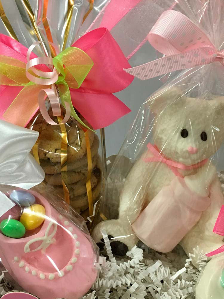 It's A Girl git box: 2 bags of mini chocolate chip cookies, solid 3D white chocolate bear, chocolate baby bootie, and 2 chocolate covered Oreos all wrapped in cello and tied with Rosa Wrap satin bow.  