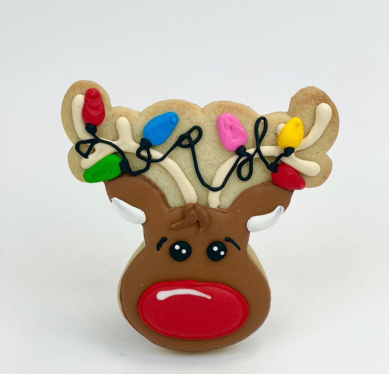 Large red nose Reindeer Sugar Cookie with colorful lights wrapped around it's antlers