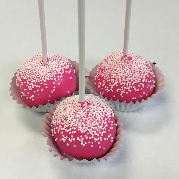 Three hot pink cake pops sprinkled with white nonpareils