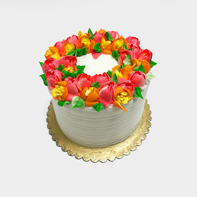 A white Pretty Spring Floral cake decorated with orange, yellow, and pink flowers on top