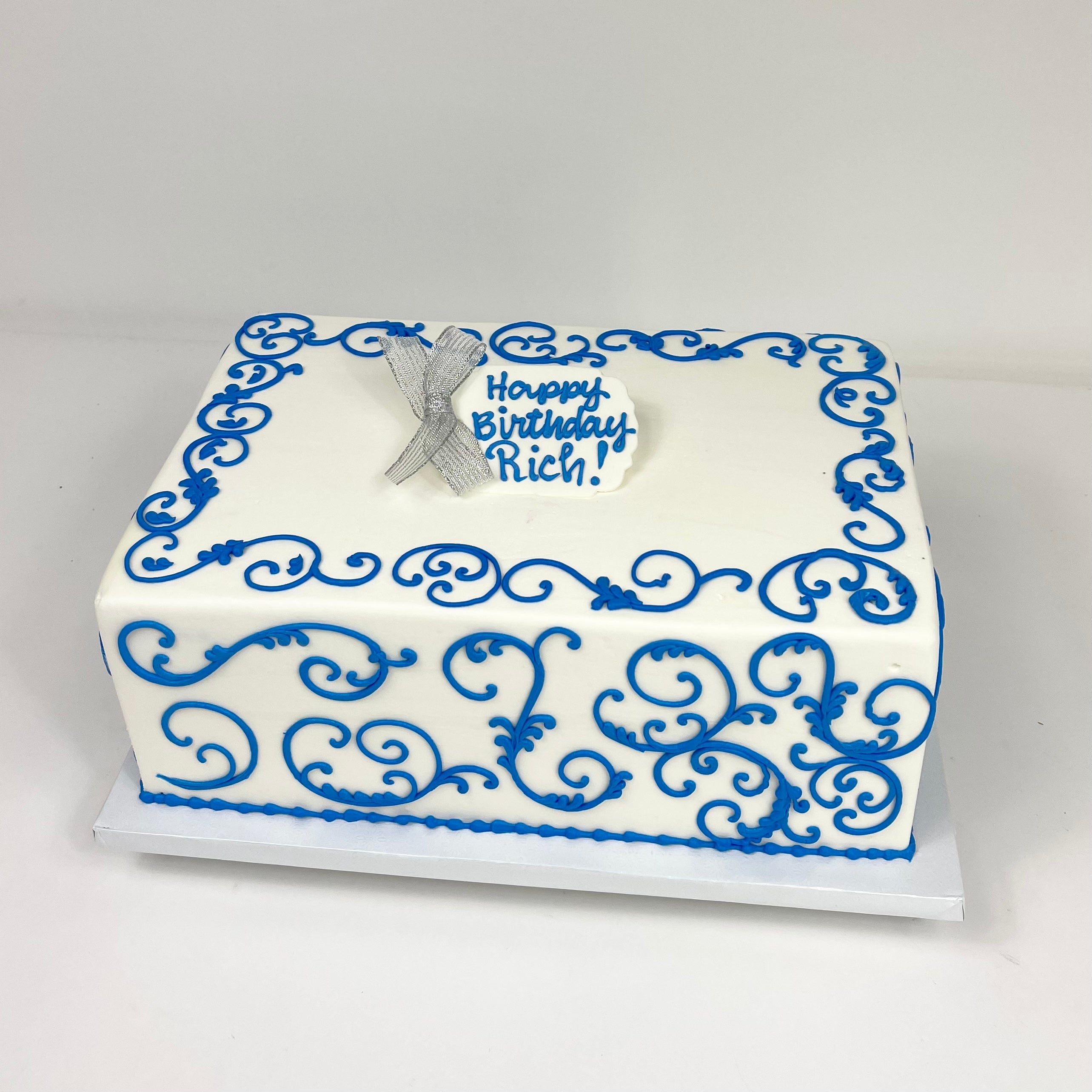 Sheet cake to serve 25 guest iced in white with pretty blue scroll. Fondant tag on top middle with wording of your choice
