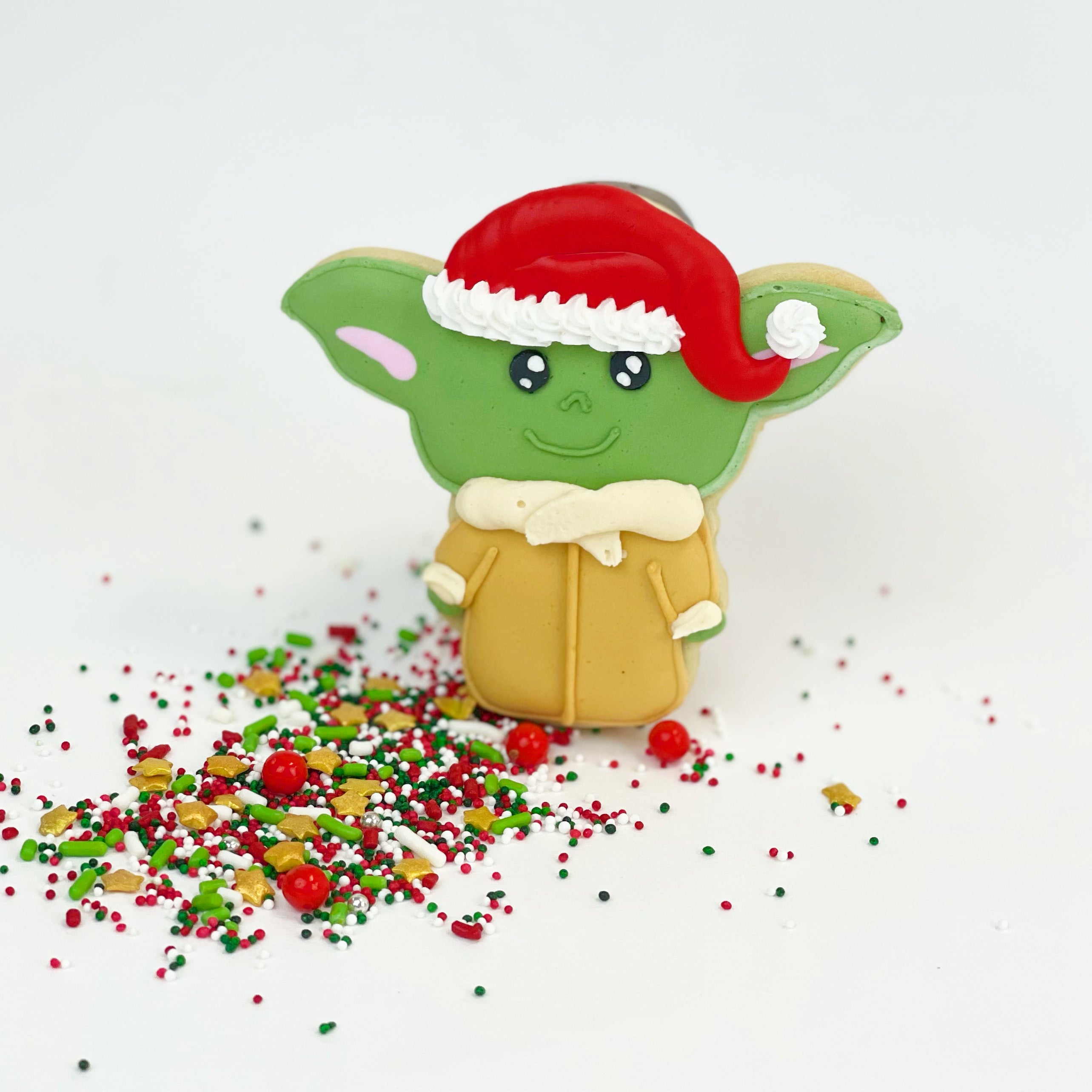 The green Child character is dressed up for Christmas, wearing a beige coat and a red Santa hat.