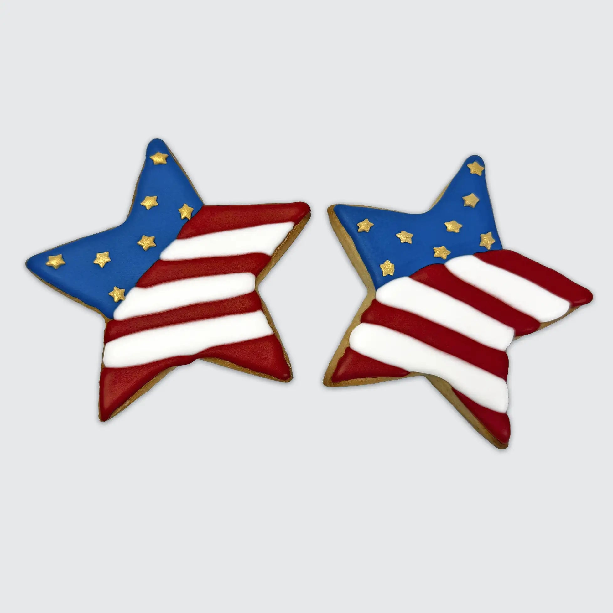 Two star-shaped cookies decorated like the American flag with red and white stripes and blue sections filled with gold stars.