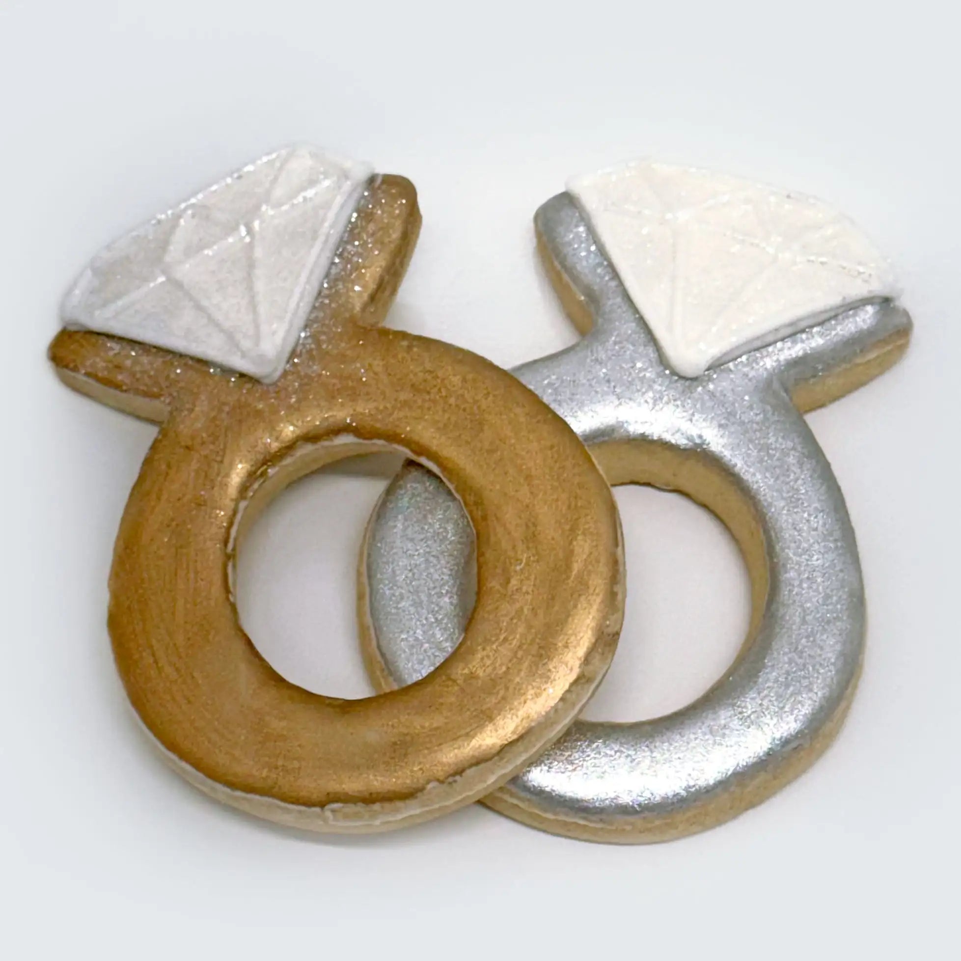 Two medium-sized ring sugar cookies: one decorated in gold, the other in silver, both adorned with white diamond accents
