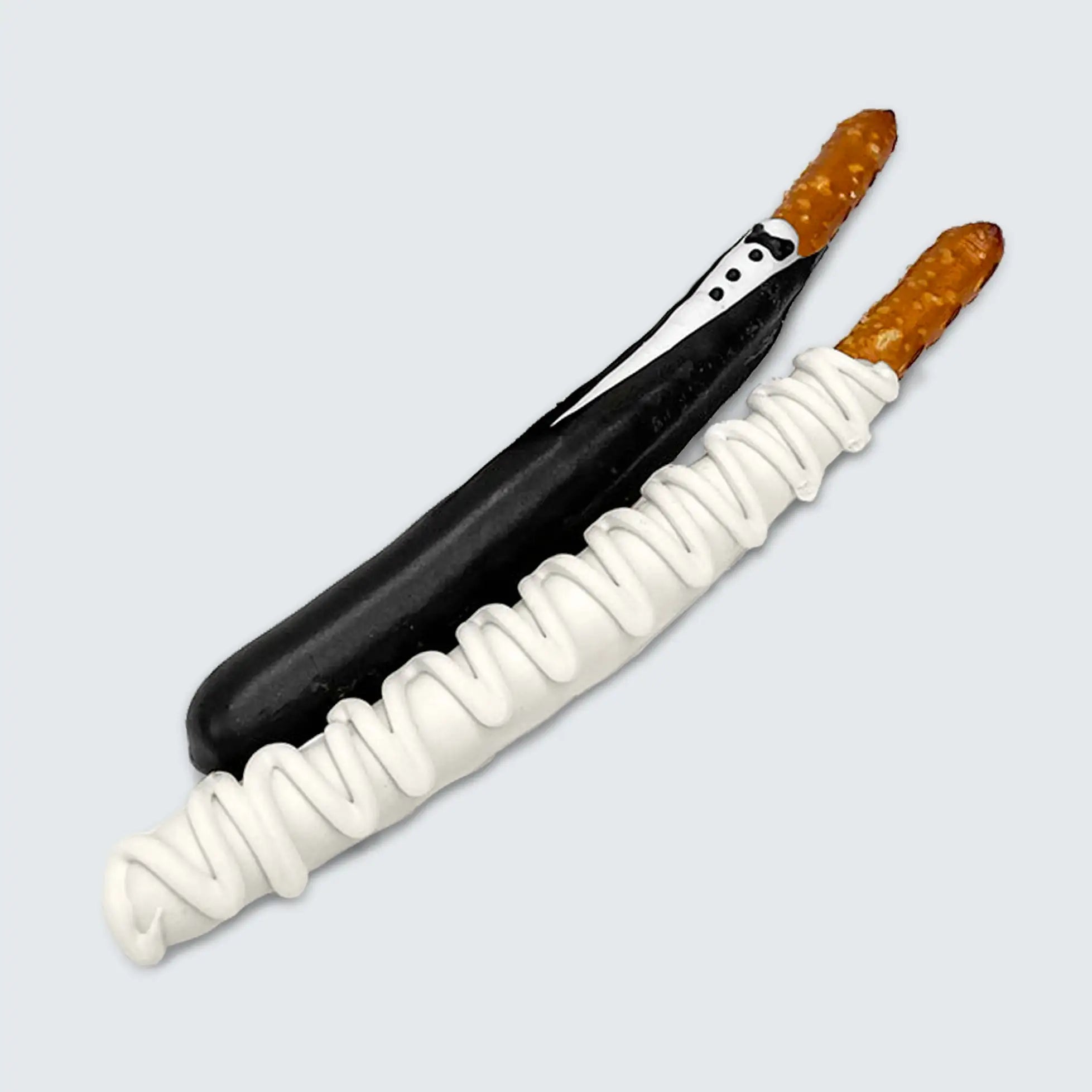 Two pretzel sticks decorated with white chocolate, one designed as a tuxedo and the other as a wedding dress.