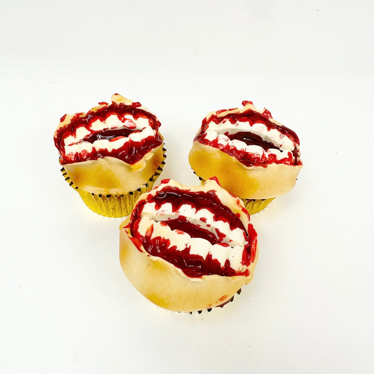 Halloween themed cupcake with white chocolate teeth clear piping gel with red dye to look like edible blood and fondant on top to look like skin