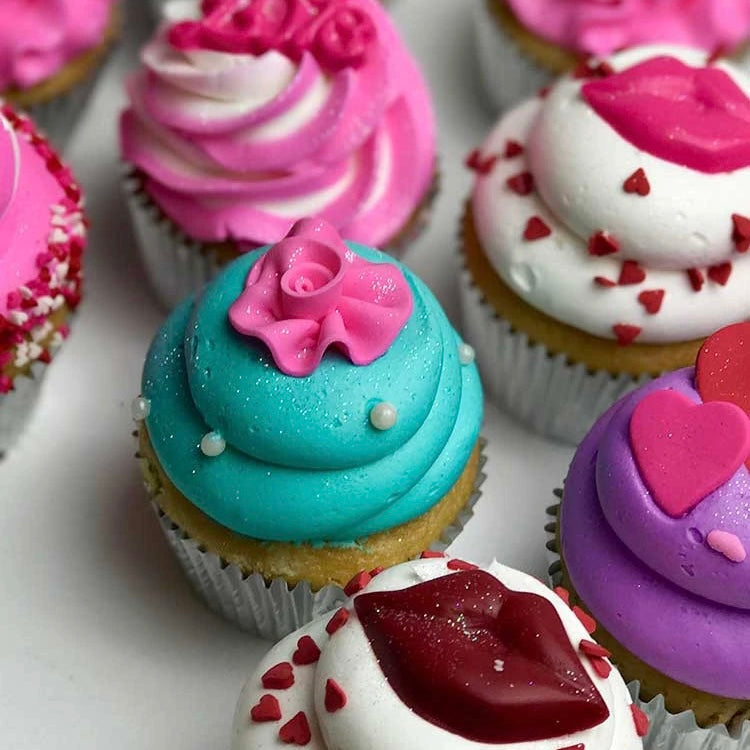 Pink, white, teal, and purple Valentine themed cupcakes, decorated with pink and red hearts, pink and red lips, and pink flower.