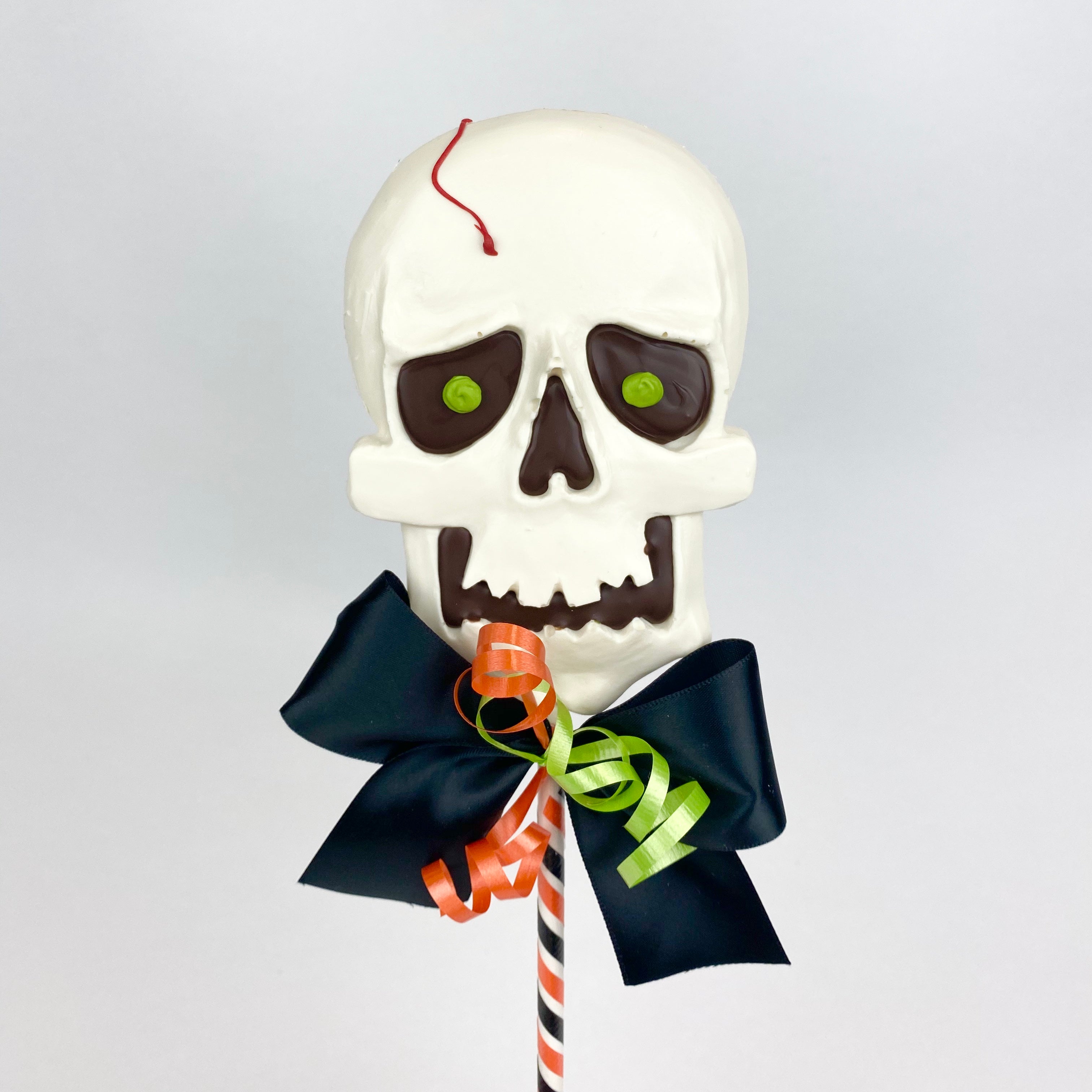 White our chocolate poured in our skull mold accented in dark chocolate amd on a 12” lolly stick