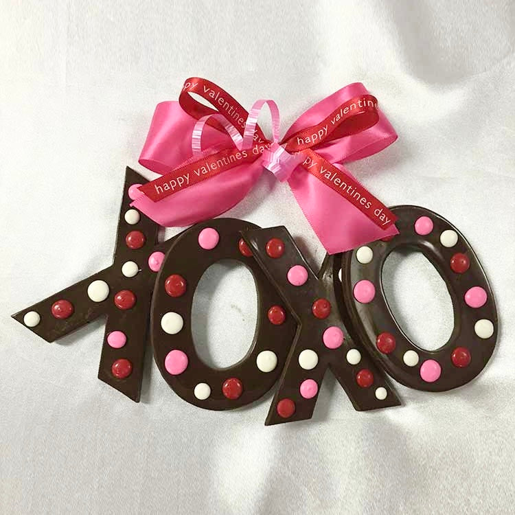 Chocolate letters decorated with red, pink and white dots and wrapped in cello and tied with a satin pink and red "Happy Valentine's Day" bows.