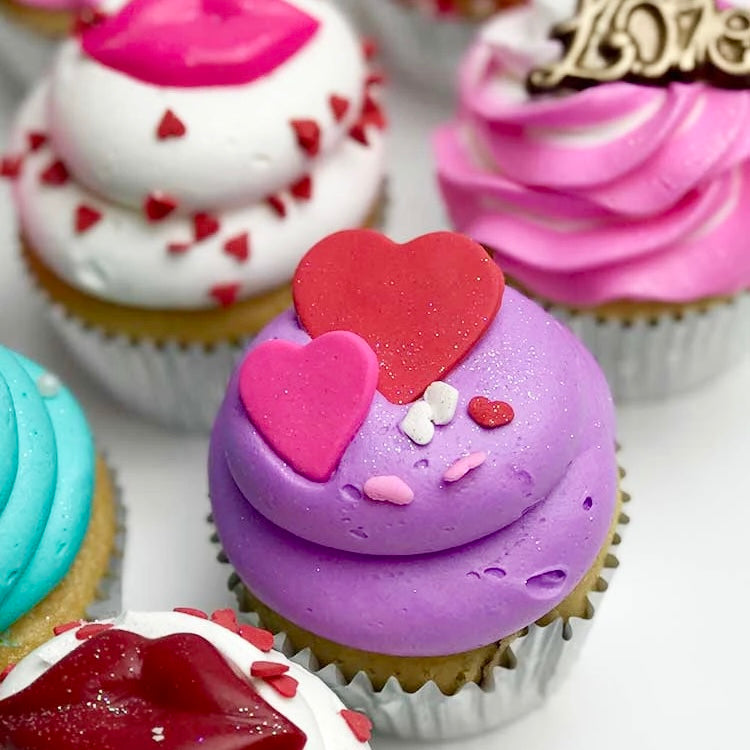 Pink, white, teal, and purple Valentine themed cupcakes, decorated with pink and red hearts, pink and red lips, pink and gold love and pink flower.