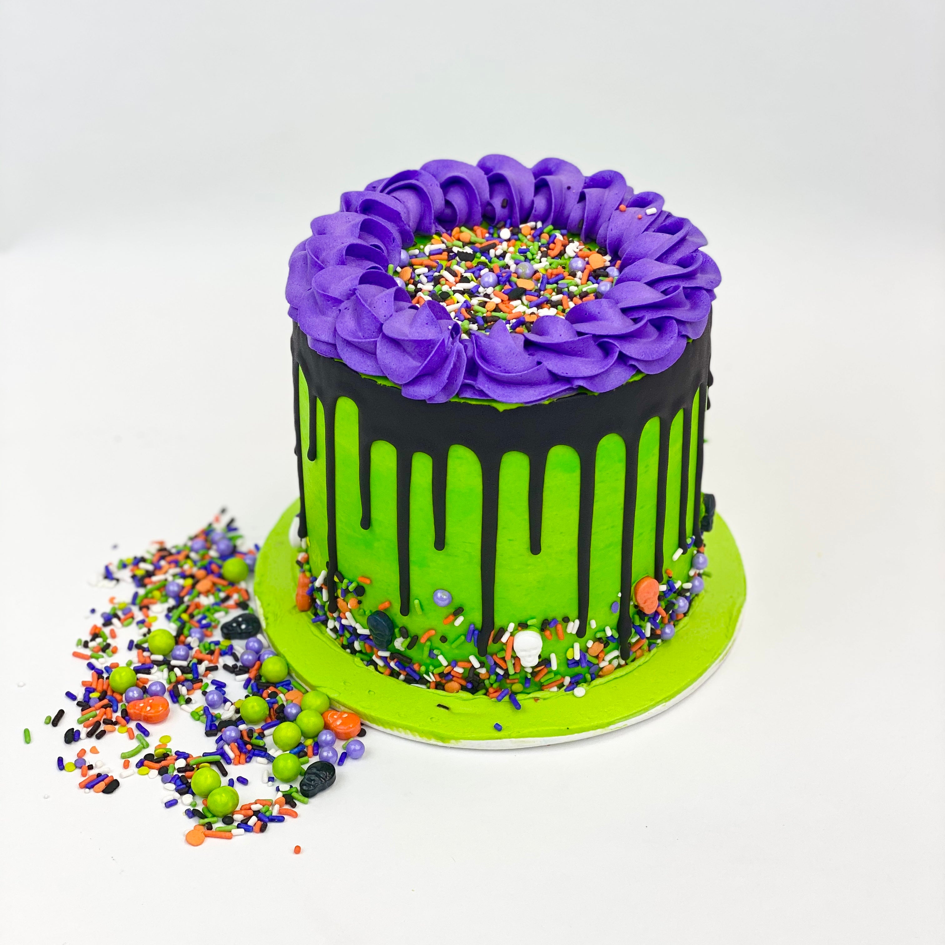 Green, purple, and black Halloween Pinata Cake with colorful candy around it