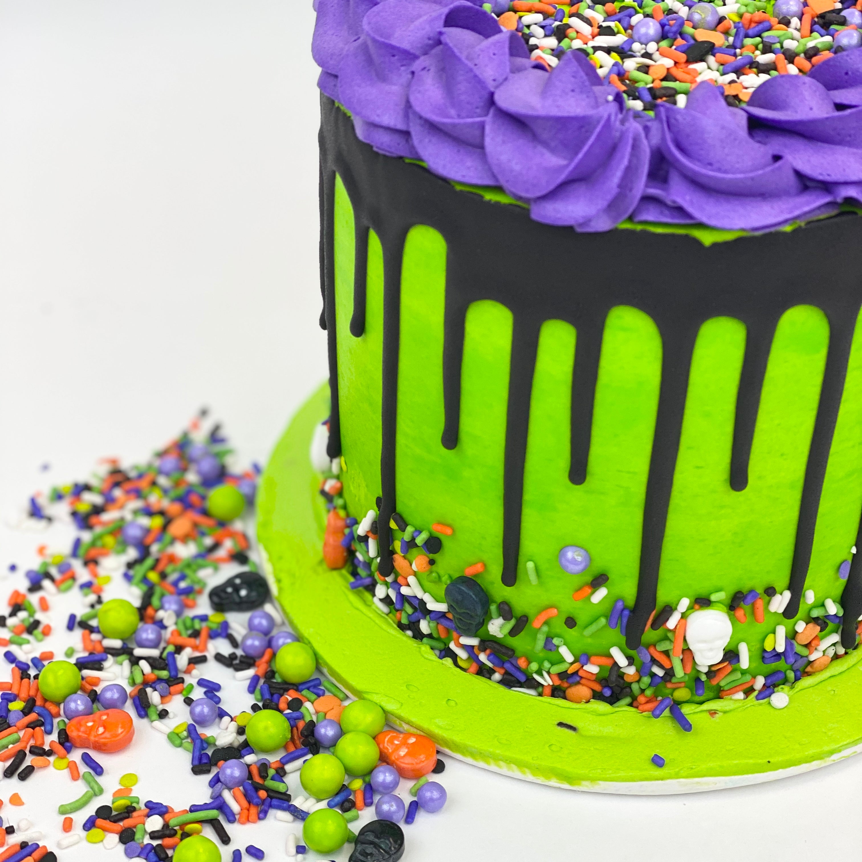 Green, purple, and black Halloween Pinata Cake with colorful candy around it