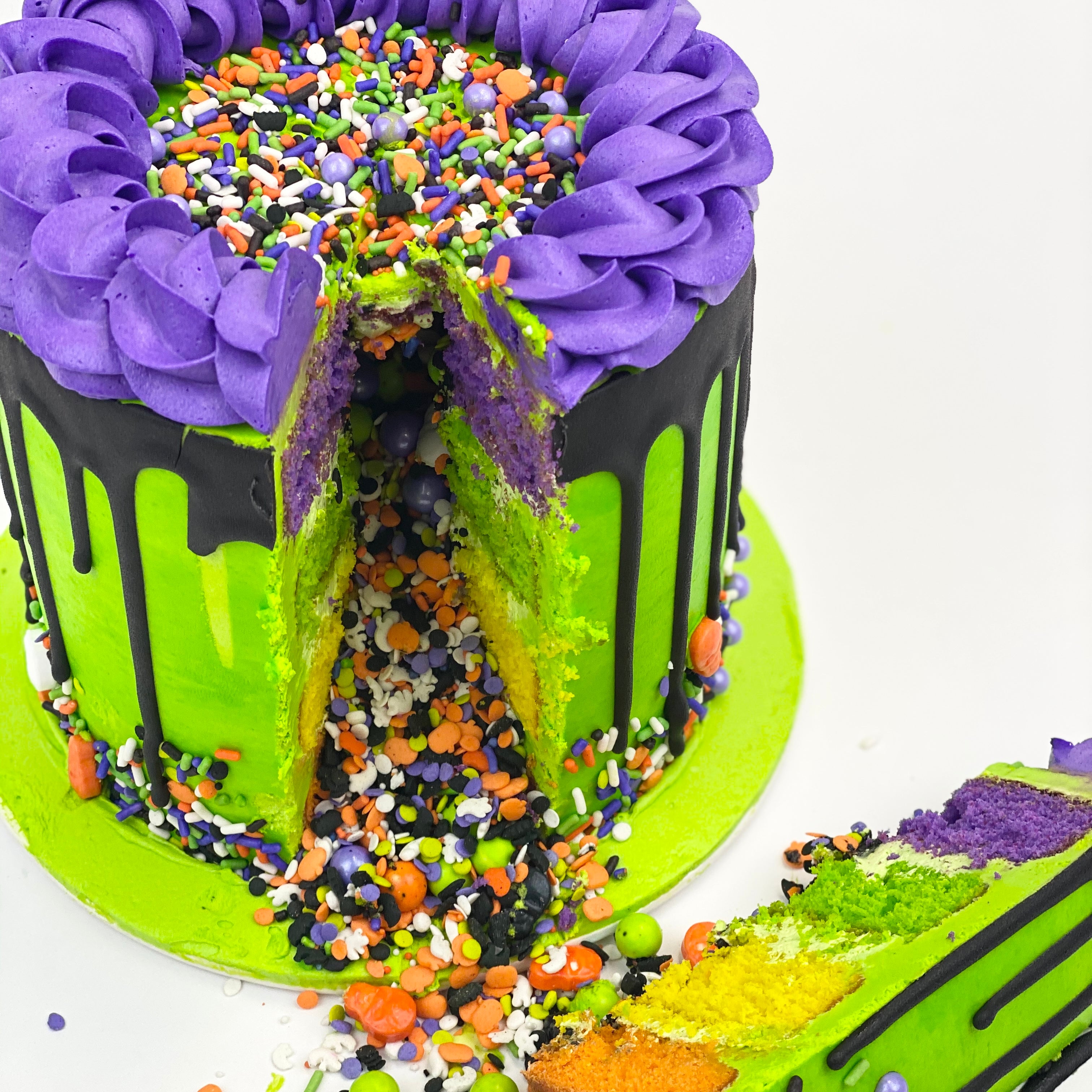 Green, purple, and black Halloween Pinata Cake, cut open with colorful candy coming out of it