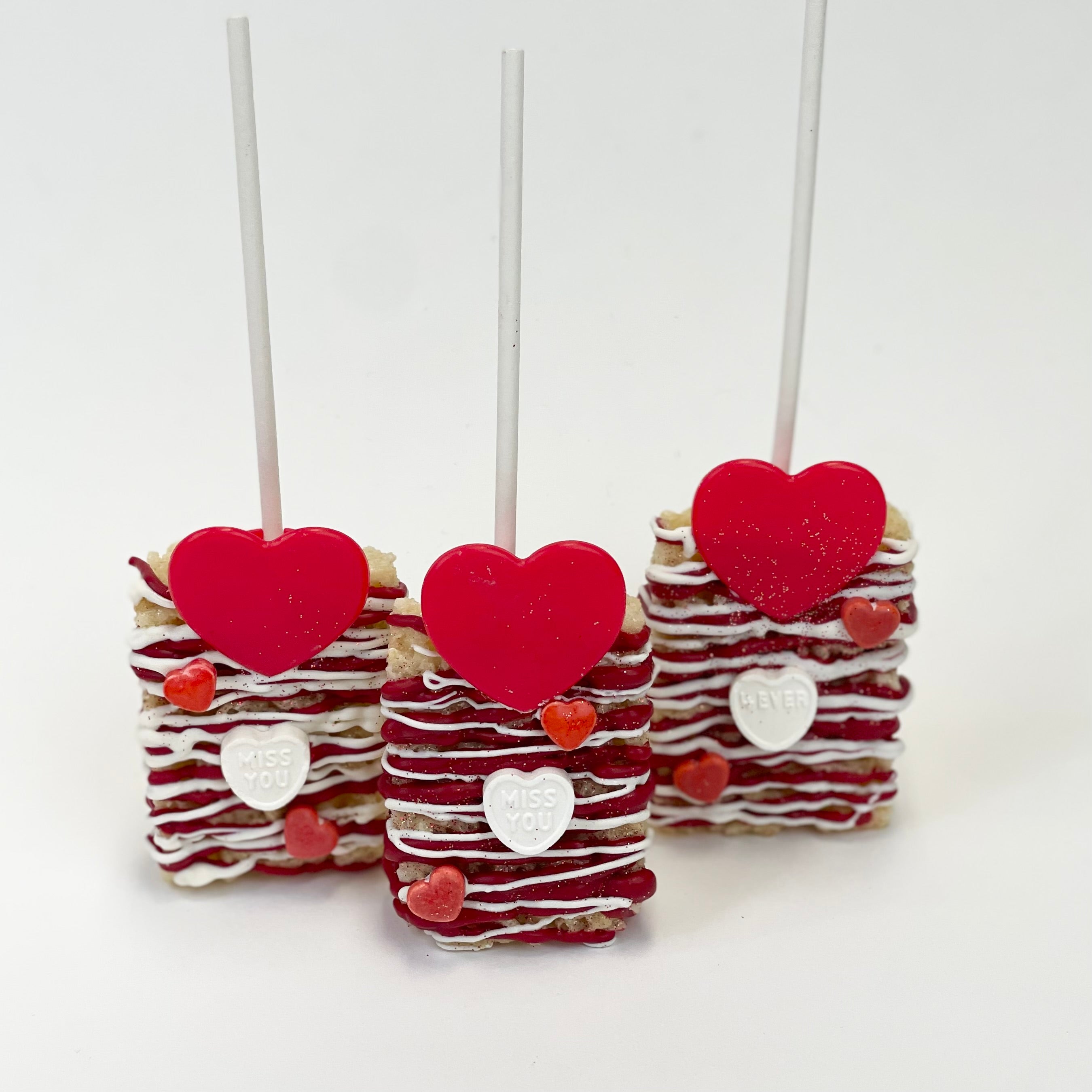 Three Valentine's Day Rice Krispy Treats Lollies decorated with red and white heart dandy.