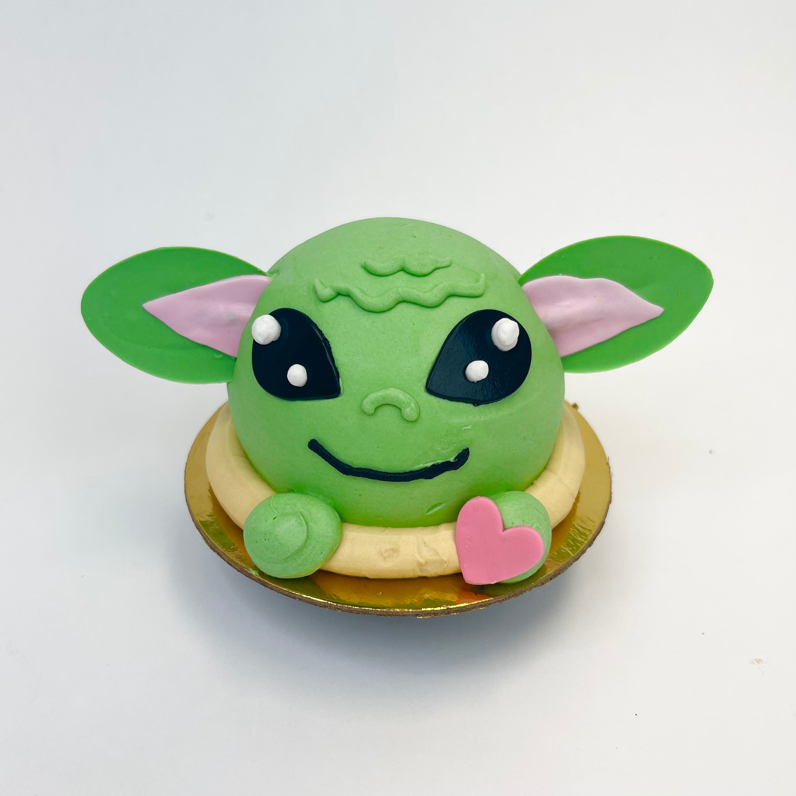 The Child is a green 3D cupcake, all dressed up for Valentine's Day and has a pink heart on it's hand.