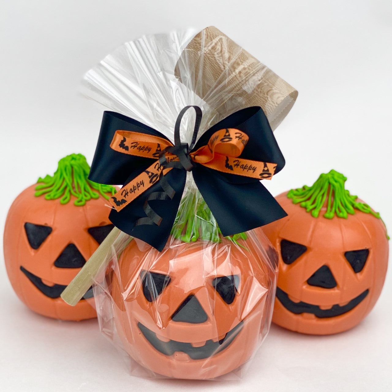 Halloween Jack-O-Lantern Piñatas, one with a mallet wrapped in cellophane with ribbons